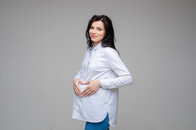 Free photo picture of a cheerful caucasian woman with black hair and pretty smile in white shirt and blue jeans posing for the camera
